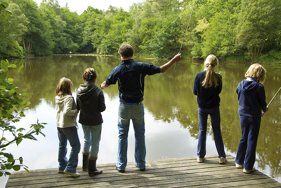 cottesmore school view of large pond water with pupils standing fishing on pond dock with rods