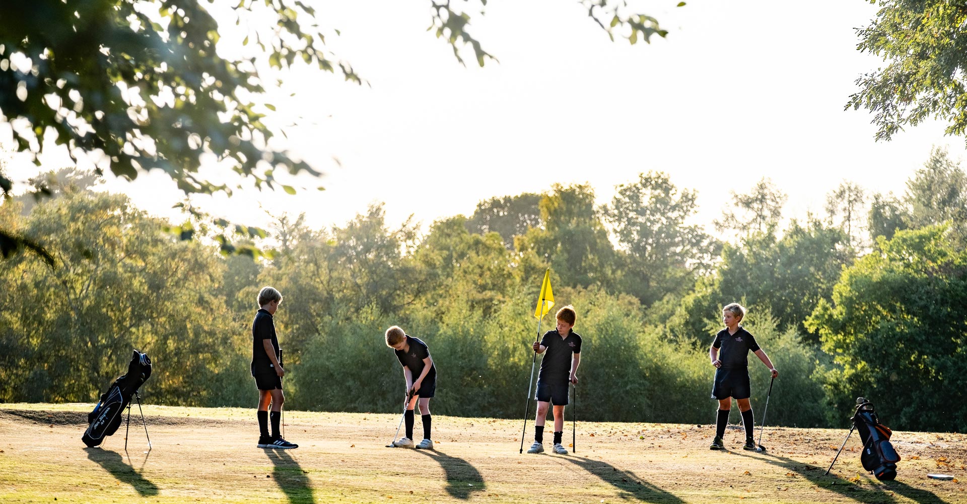 cottesmore school male pupils in navy blue polos and sports kit playing golf putting on the green