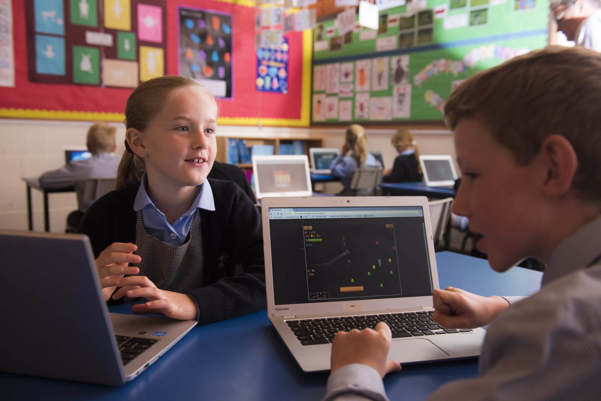 cottesmore school female and male pupil talking using laptops learning in IT information technology classroom