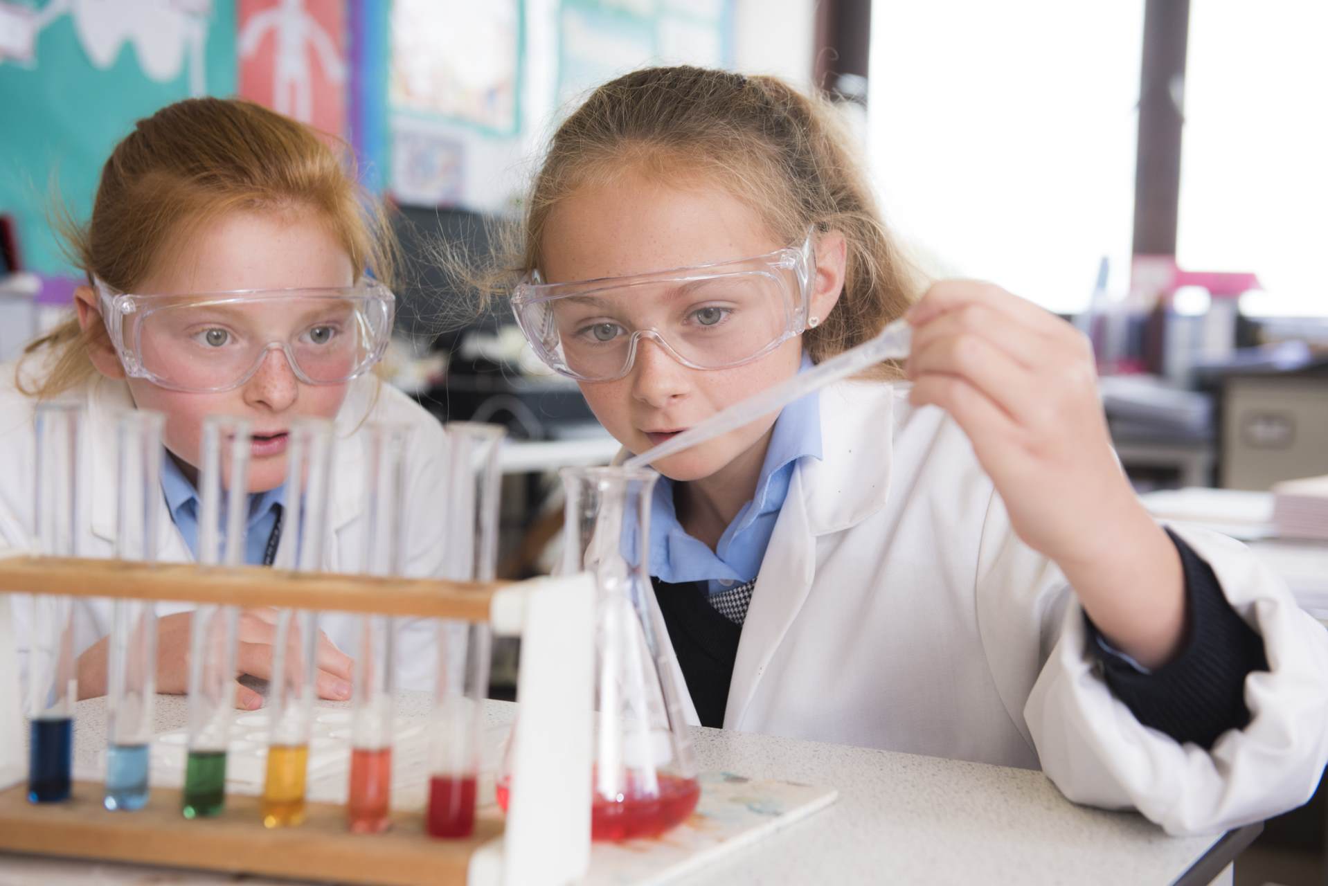 cottesmore school pupils in lab coats safety goggles glasses pipetting chemicals from test tubes into a conical flask