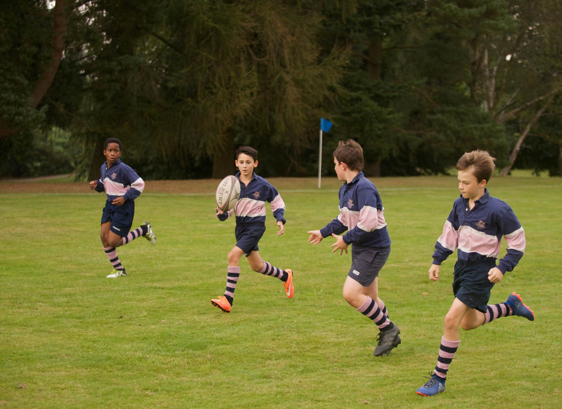 cottesmore school male pupils in rugby sports kit running playing with ball in field