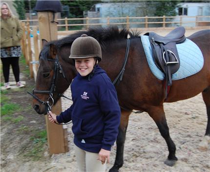 cottesmore school female pupil holding reigns of horse leading out of arena for equestrian